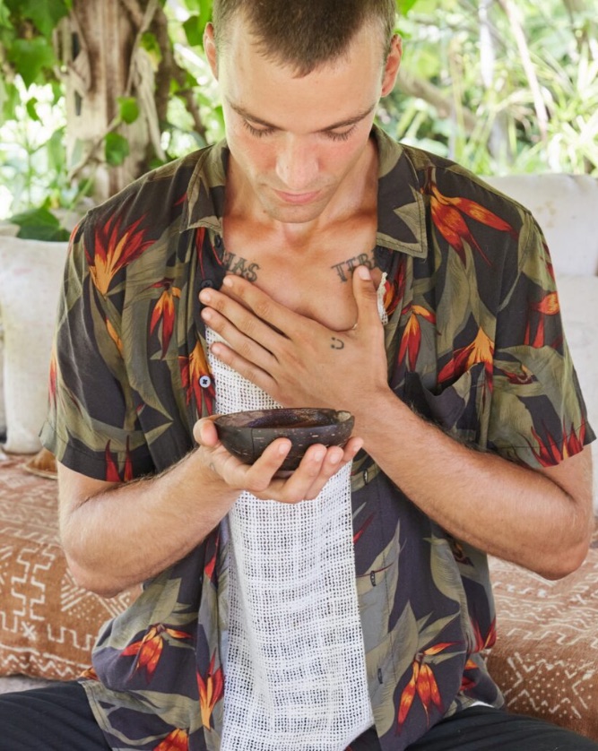 Marc Lüloh holding a ceremonial cacao bowl, eyes lowered in a moment of quiet preparation.